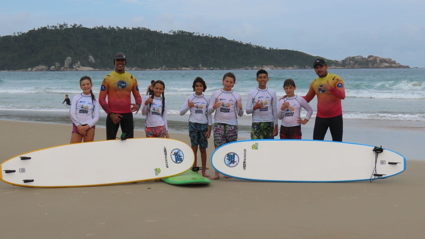 Turma infantil com pranchas na areia