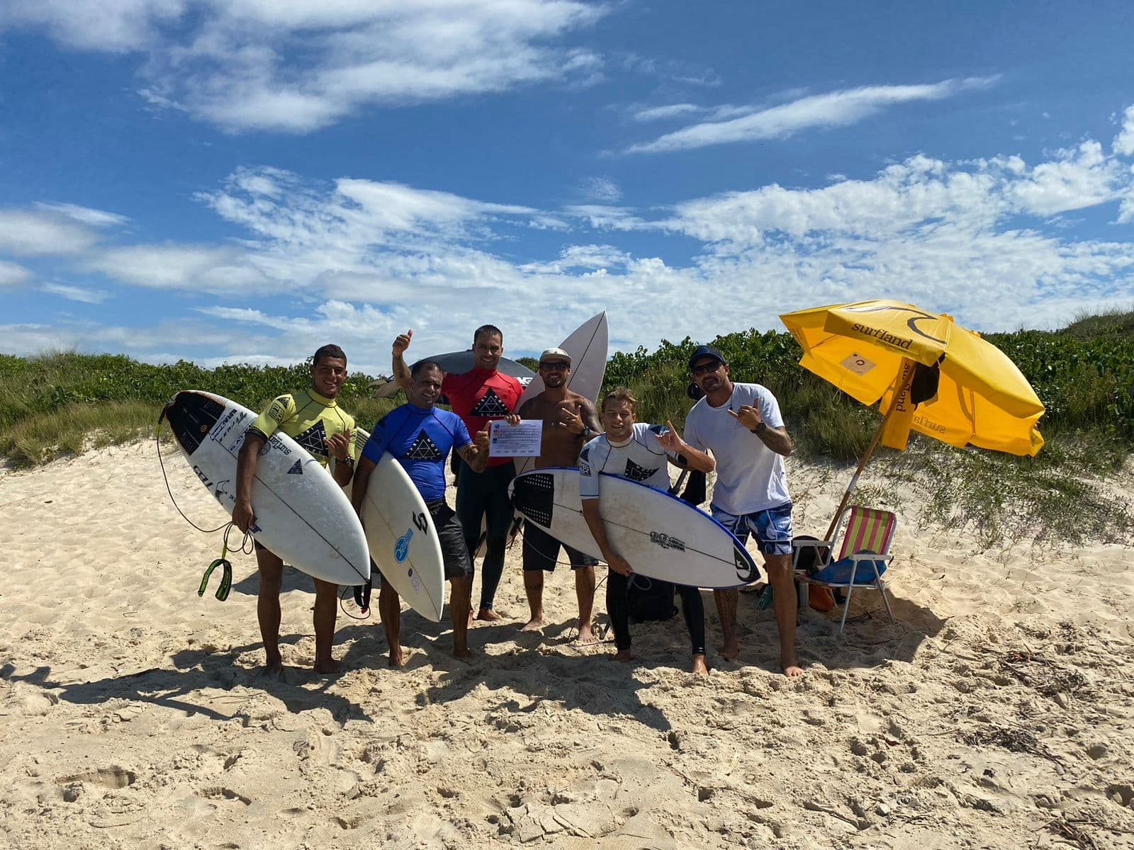 Alunos alinhados com as pranchas na beira do mar